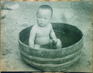 桶で水浴びをする子供