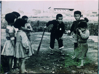 カメラを持ってはいポーズ　バットを持った子供、むこうには阿波中島の駅が見える