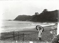 海岸を傘をさして歩く女性