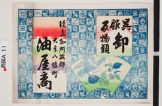引札絵柄：宝尽くしの背景・扇面に茄子と鷹
商店場所：徳島県阿波郡大字八幡町
商店名称：油屋商
商売内容：呉服反物類卸